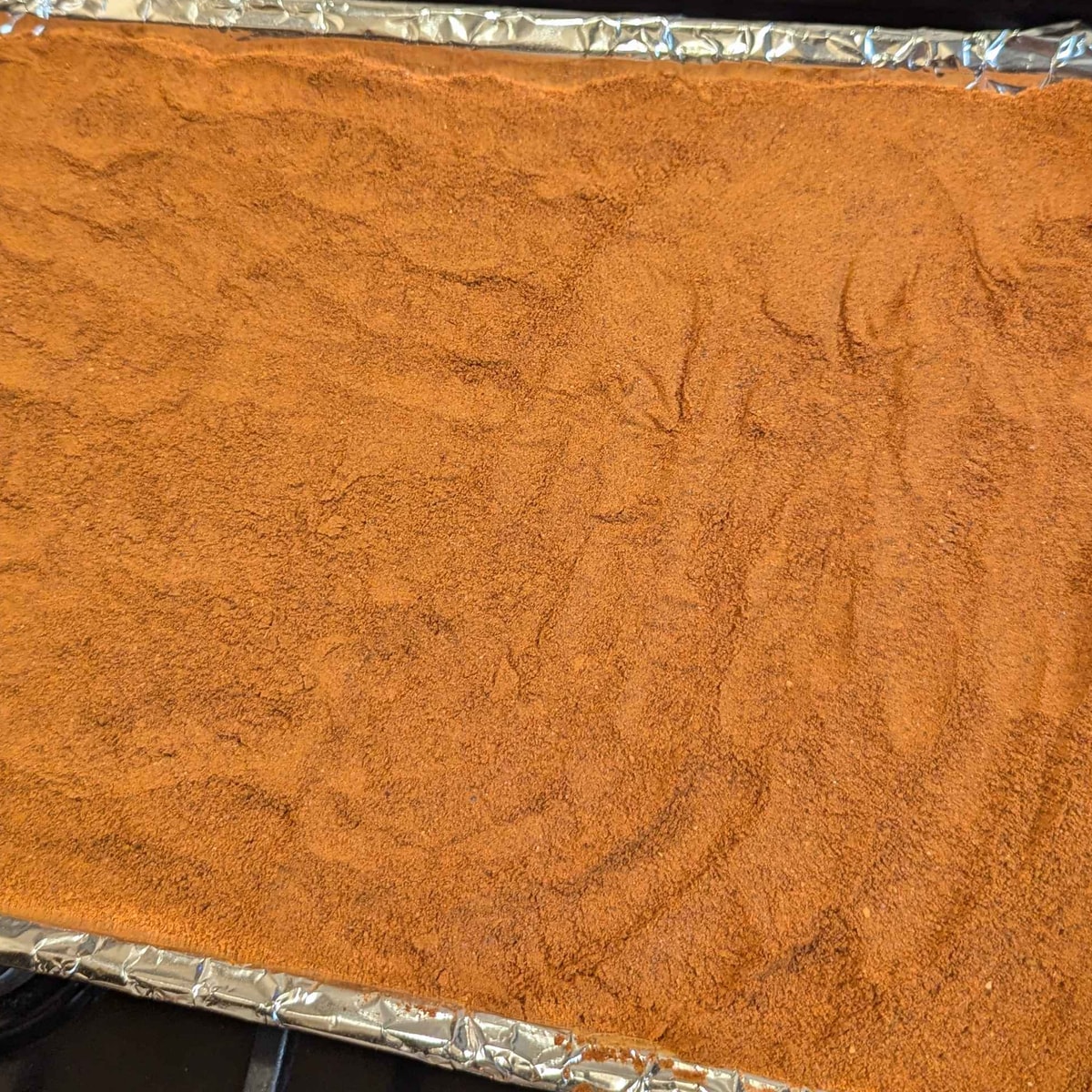 Freshly ground paprika filling a foil-lined tray edge to edge.